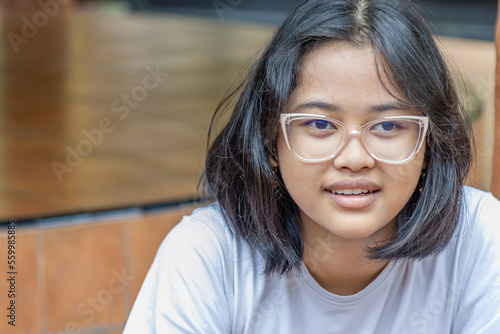 Closed up of a young Asian girl who is smiling and wearing minus glasses