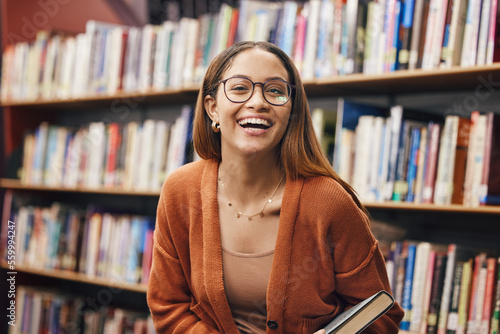 Face, student and woman in library with book ready for learning. Portrait, university education and happy female from Brazil standing by bookshelf for studying, knowledge and literature research.