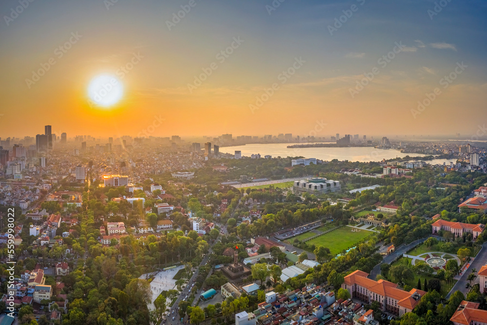 Naklejka premium DOWNTOWN BA DINH SQUARE, HANOI SKYLINE SHOWING SEVERAL PROMINENT BUILDINGS AND BRIDGE UNDER A BLUE SKY. VIETNAM