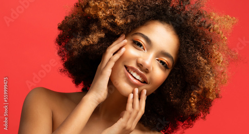 Young elegant african american woman with afro hair. Female model touching her face with her fingers. Glamour makeup. photo