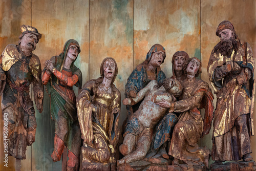 Venzone, Italy - December 29, 2022: Medieval wooden group sculpture of the lamentation of the dead Christ by Giovanpietro da Mure preserved in the cathedral of Saint Andrew apostle in Venzone