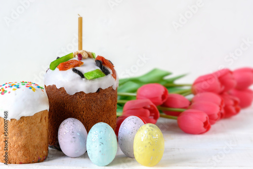 Painted Easter eggs, tulips and cakes on white wooden table