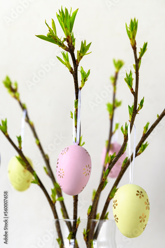 Painted Easter eggs hang on branches on white background