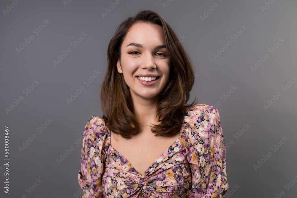 Fototapeta premium Portrait of a young woman on a gray background. Emotional portrait of a model in a stylish shirt
