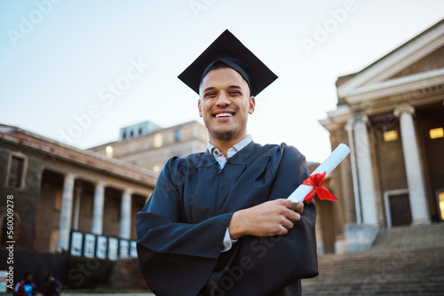 University, graduation and happy man with a diploma scroll standing outdoor of his campus. Education, scholarship and male graduate from Mexico with academic certificate or degree for college success photo