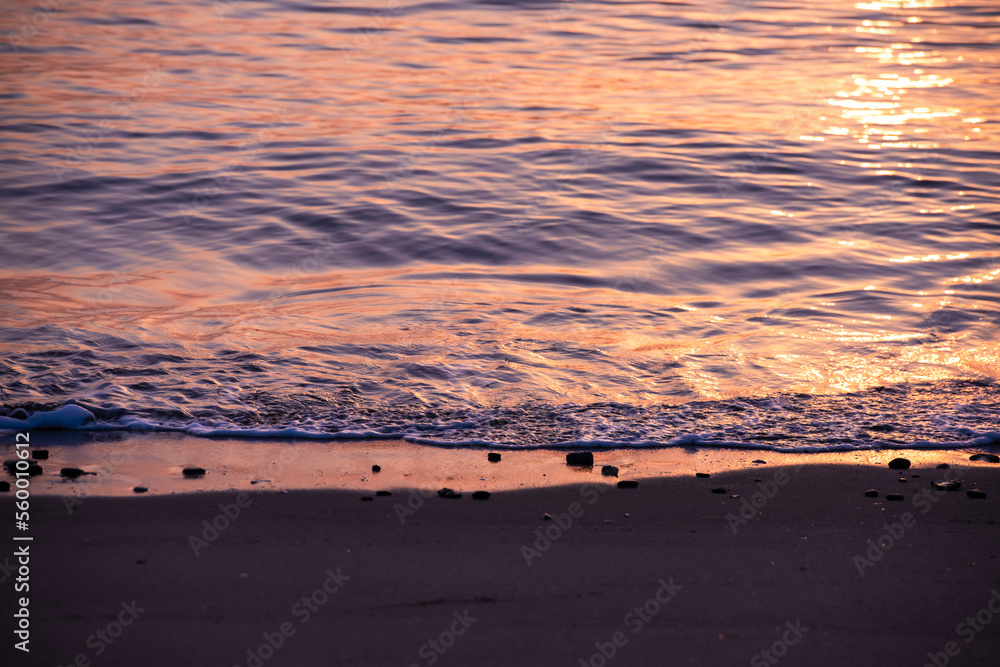 Naklejka premium 昇る朝日に照らされてキラキラと輝く砂浜海岸