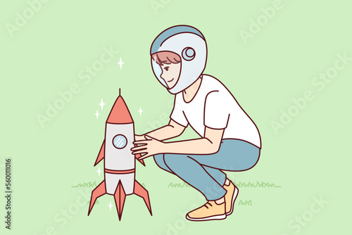 Little boy squatting near toy rocket representing launching spaceship to another planet. Child plays as astronaut, wanting to work in space industry and launch intergalactic ships. Flat vector design 