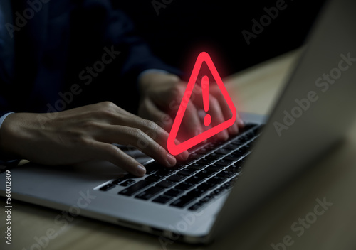 Businessman using laptop showing warning triangle and exclamation sign icon Warning of dangerous problems server error photo
