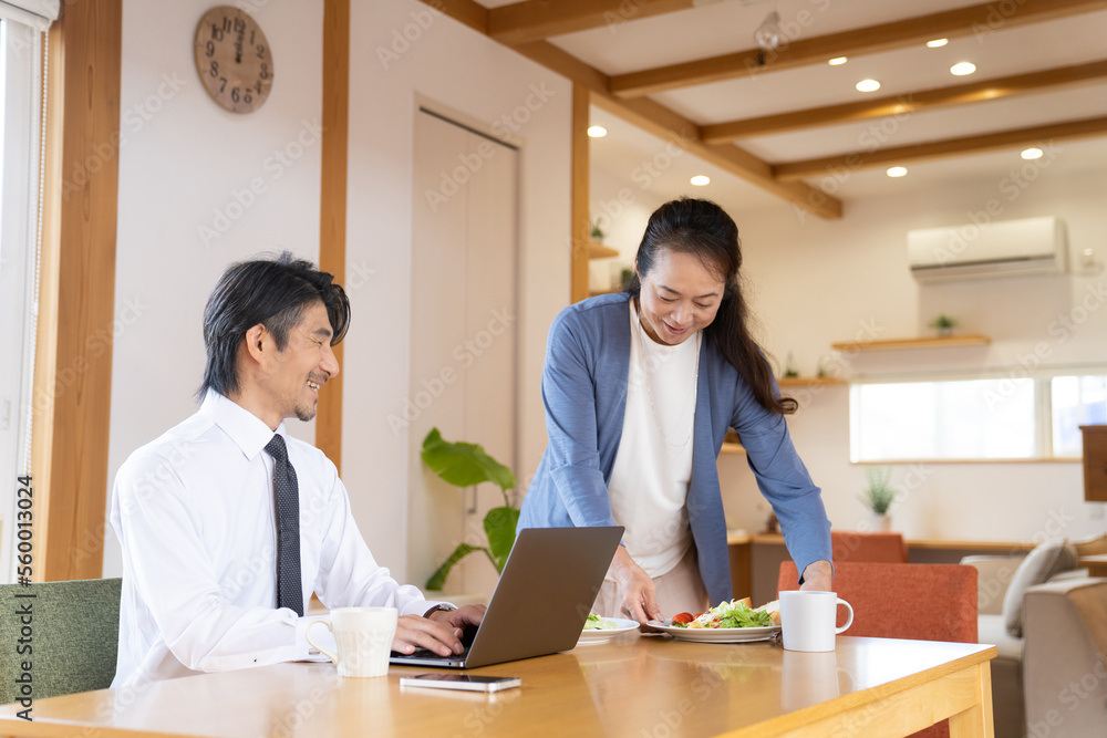 Fototapeta premium 仕事をする男性と食事を運ぶ女性