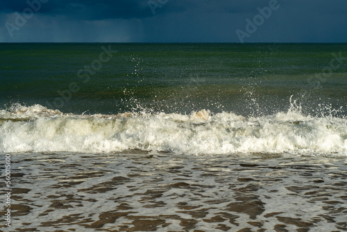 Small sea waves with splashes of water flying up on the coast. A relaxing holiday on the beach. Memories of a summer vacation. photo