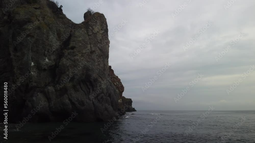 Aerial cloudy sea. Drone view of peaceful calm dark blue sea water surface, cloudy sunset or sunrise sky and silhouettes of mountains. Storm Large freight dark gloomy rain clouds over a calm sea.