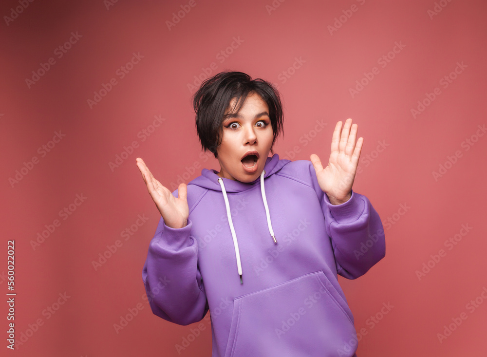 An image of an excited, screaming young woman standing isolated on a pink background. A viewing camera. studio portrait An image of an excited, screaming young woman standing isolated on a pink background. A viewing camera. studio portrait