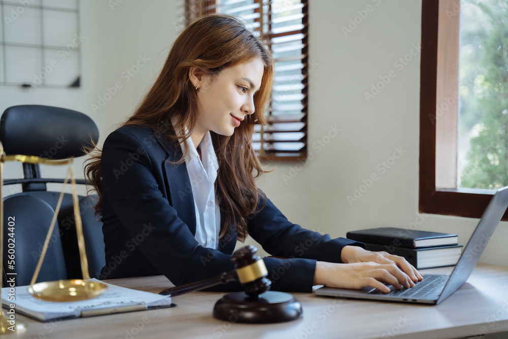 Justice and law concept. Female in a courtroom with the gavel working with digital tablet computer docking keyboard on wood table. Justice and law concept. Female in a courtroom with the gavel working with digital tablet computer docking keyboard on wood table.