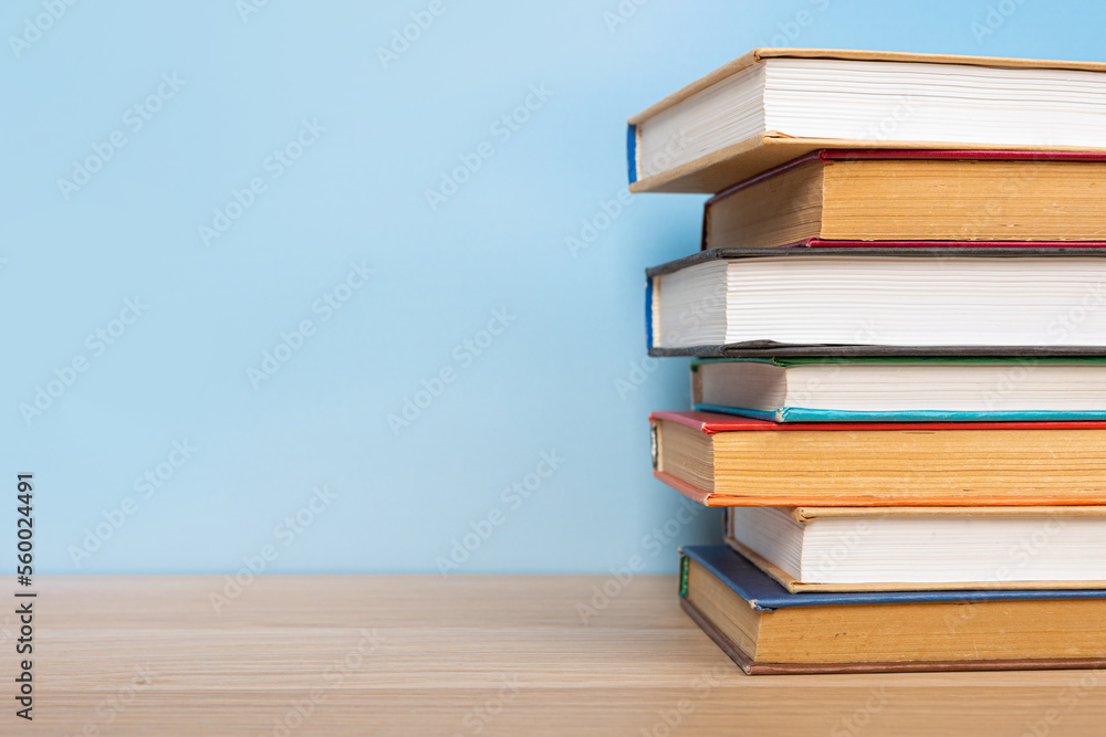 Stack of books in the colored cover lay on the wooden table and blue backround. Education learning concept Stack of books in the colored cover lay on the wooden table and blue backround. Education learning concept