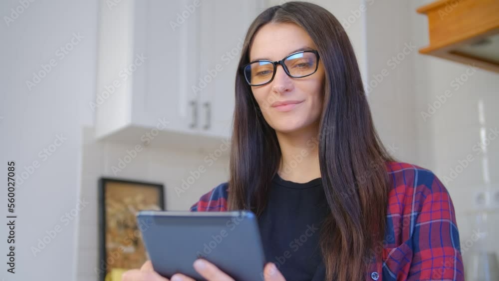 Young brunette woman browsing internet on tablet pc at home. Dark haired female person reading ebook on portable gadget Young brunette woman browsing internet on tablet pc at home. Dark haired female person reading ebook on portable gadget