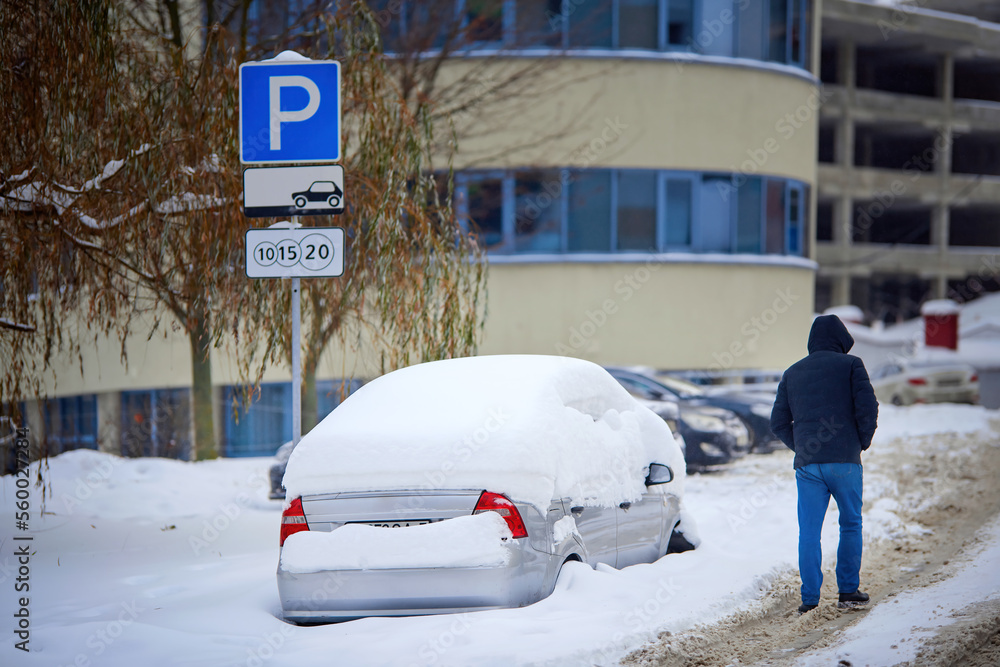 Car on paid parking lot stuck in deep snow, car buried under snow after