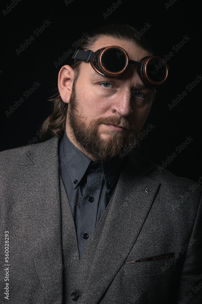 Obraz premium charismatic man in a classic suit and steampunk goggles on a black background stylish Portrait