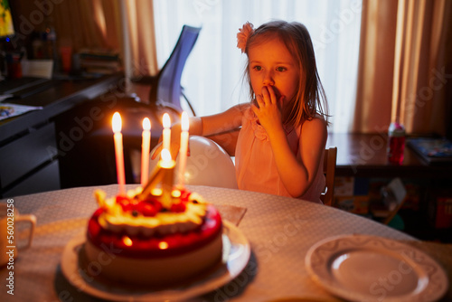 Happy little girl celebrating her fourth birthday and making a wish