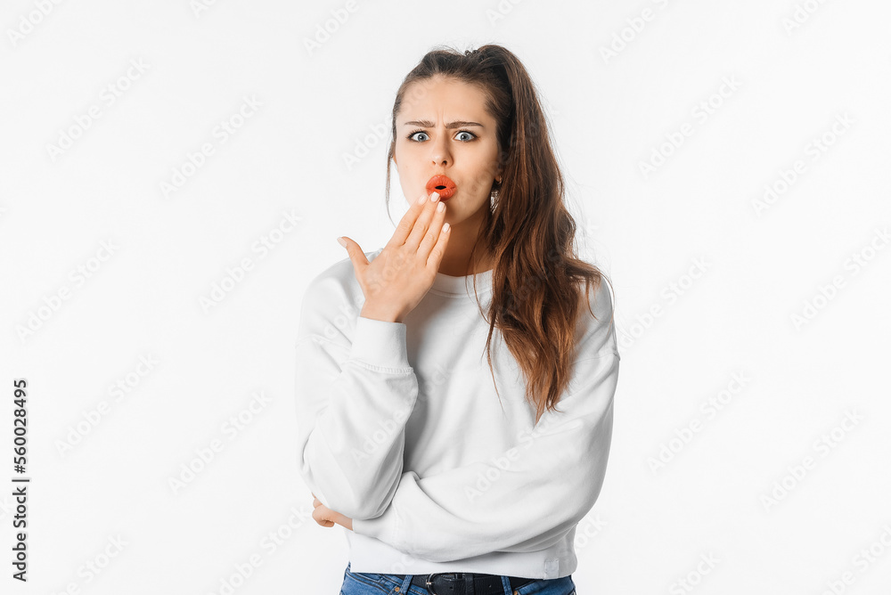 Ouch. Amazed young woman showing Oops expression at the camera. Portrait of young girl with long hair, arm cover mouth, standing against white studio background Ouch. Amazed young woman showing Oops expression at the camera. Portrait of young girl with long hair, arm cover mouth, standing against white studio background