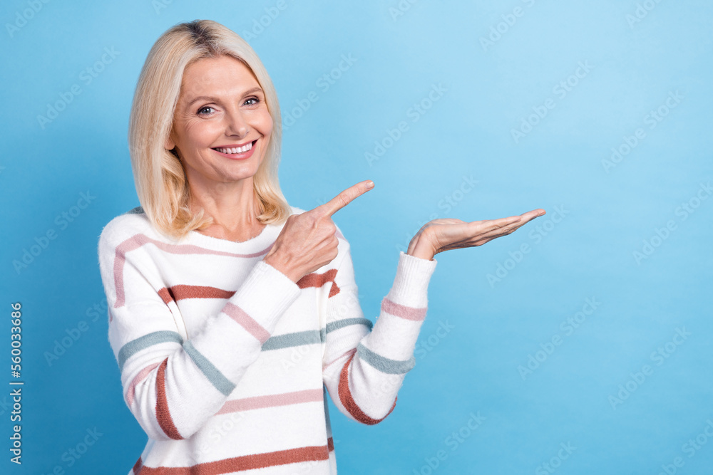 Photo of sweet pretty lady wear striped pullover pointing holding arm empty space isolated blue color background Photo of sweet pretty lady wear striped pullover pointing holding arm empty space isolated blue color background