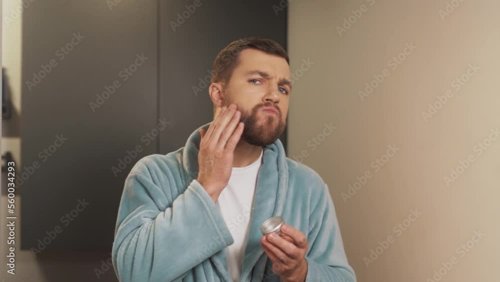Portrait of a man applying the device to his beard and rubbing it with his hands Portrait of a man applying the device to his beard and rubbing it with his hands