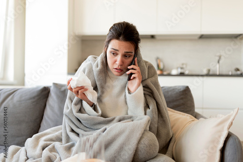 Φωτογραφία Young sick woman calls the doctor  on the phone to give her symptoms and to make a house call