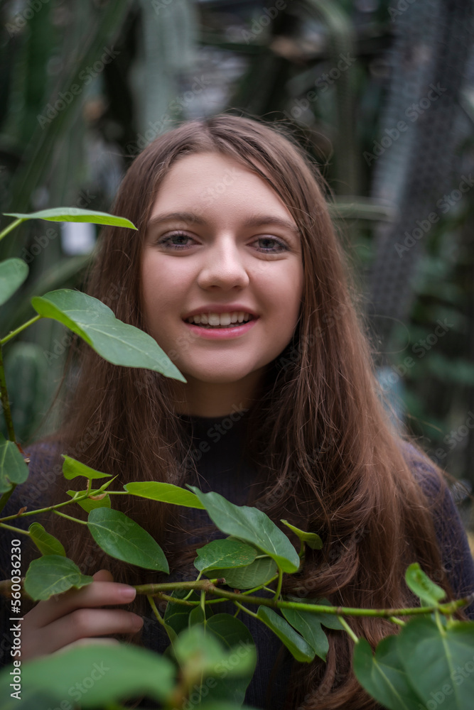Portrait of happy beautiful young science student. Youn girl in a greenhouse with tropic plants. She is studiing plants Portrait of happy beautiful young science student. Youn girl in a greenhouse with tropic plants. She is studiing plants