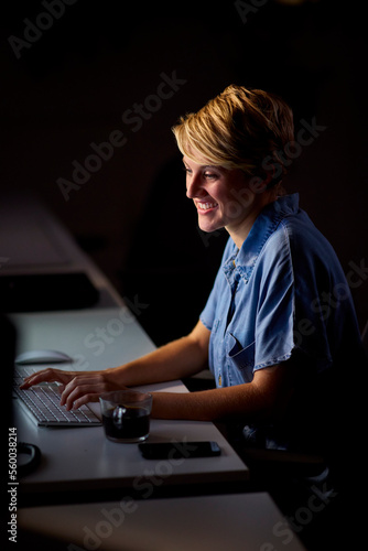 Businesswoman Working Late In Office With Face Illuminated By Computer Screen