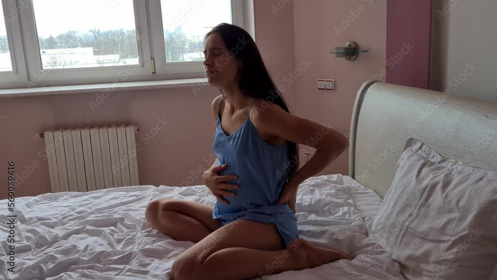 Pregnant woman suffers from lower back pain on bed. Pregnancy pain and first labor pains Pregnant woman suffers from lower back pain on bed. Pregnancy pain and first labor pains