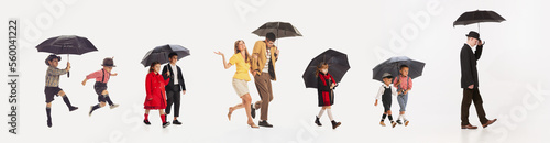 People walking with umbrella. Composite image with portraits of man, woman and kids strolling under umbrella isolated over white background. photo