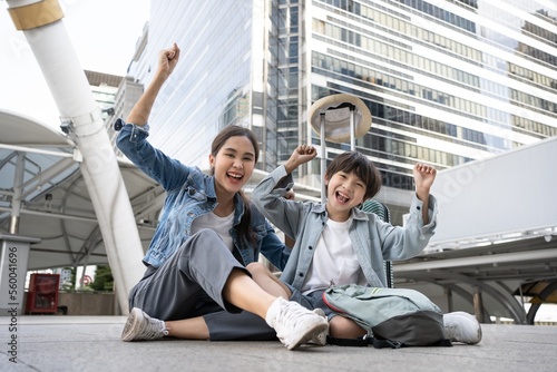  Asian American single mother with her son cheerful at the city. Mom hug and carry her son. Preparing to send her children back to school in morning. Education and Back to school concept. Happy family