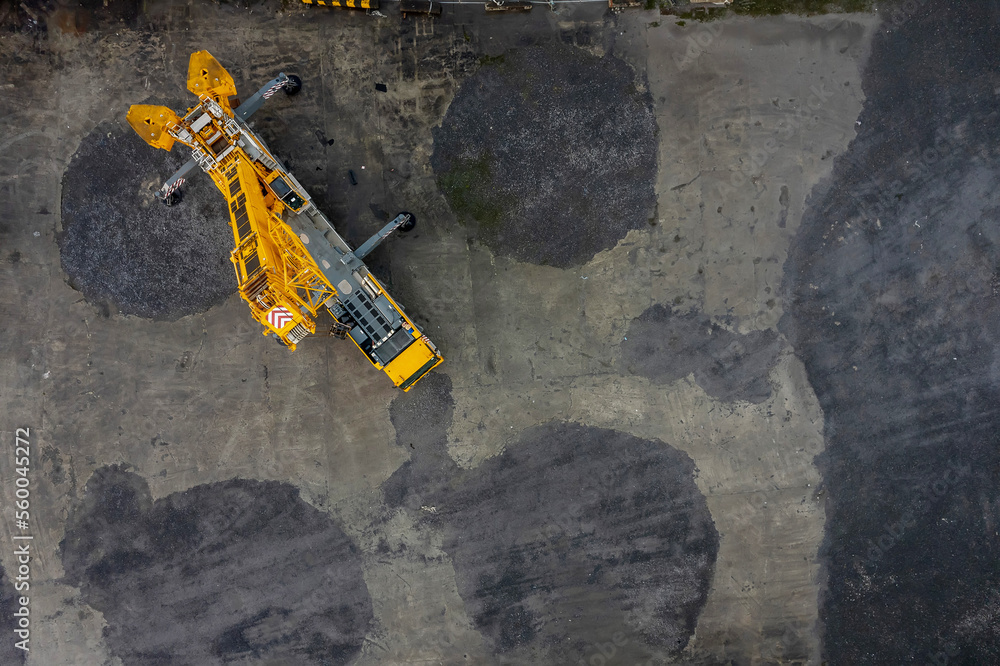 Tall yellow color track crane in a yard. Heavy machinery industry. Aerial view.
