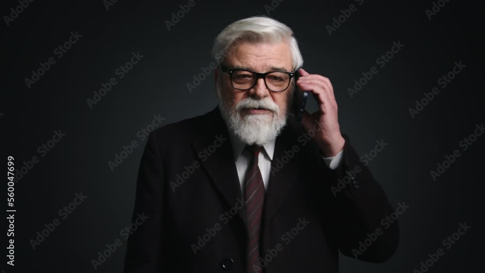 Close-up view of a senior businessman using his smartphone indoors. Portrait of gray-haired man holding his gadget while speaking. High quality 4k footage Close-up view of a senior businessman using his smartphone indoors. Portrait of gray-haired man holding his gadget while speaking. High quality 4k footage
