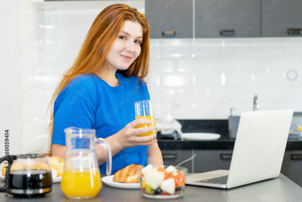 Beautiful corpulent woman working at computer in the morning at breakfast Beautiful corpulent woman working at computer in the morning at breakfast