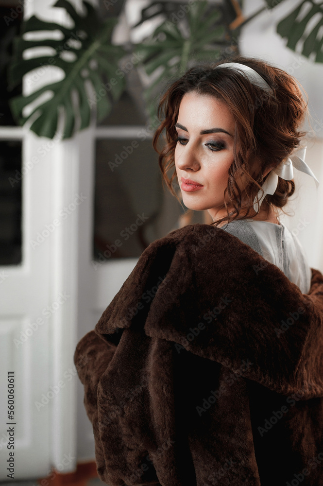 sexy girl dressed in a fur coat and posing indoors on the background of the door; warm long fur coat sexy girl dressed in a fur coat and posing indoors on the background of the door; warm long fur coat