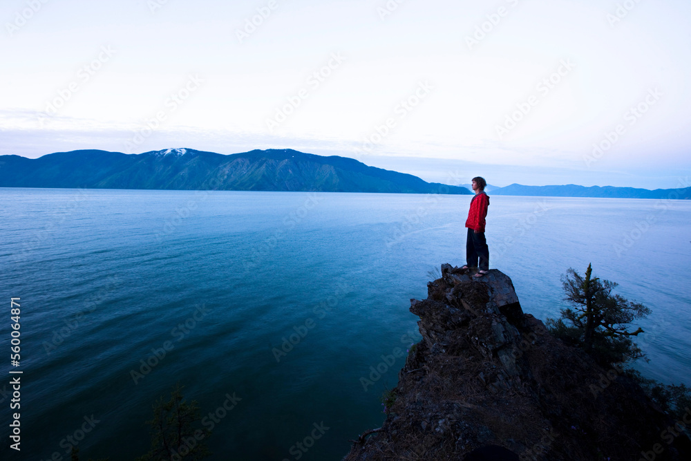 A handsome man peacefully stands on the edge of a cliff watching the sun rise over the lake in Idaho. A handsome man peacefully stands on the edge of a cliff watching the sun rise over the lake in Idaho.