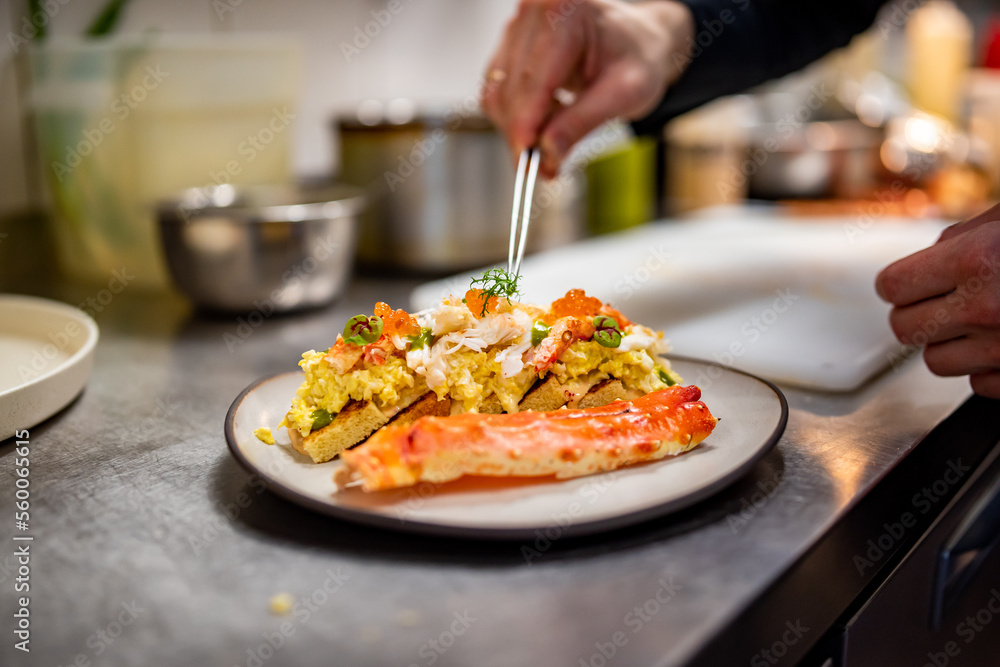 chef cooking brioche with scrambled eggs, caviar and crab meat on kitchen chef cooking brioche with scrambled eggs, caviar and crab meat on kitchen
