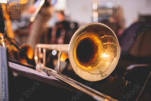 View of a golden trombone before the concert, view of a trombone player trombonist with musical jazz band group performing in the background photo