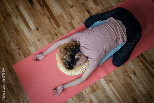 One adult caucasian woman practice restorative yoga at home