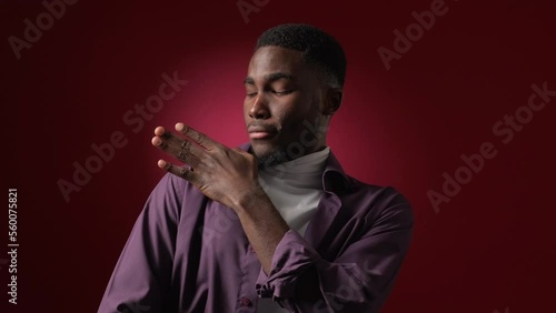 Arrogant gesture. Disgust expression. Negative rejection. Snobbish careless man brushing dust dirt off shoulder on dark red copy space background. photo