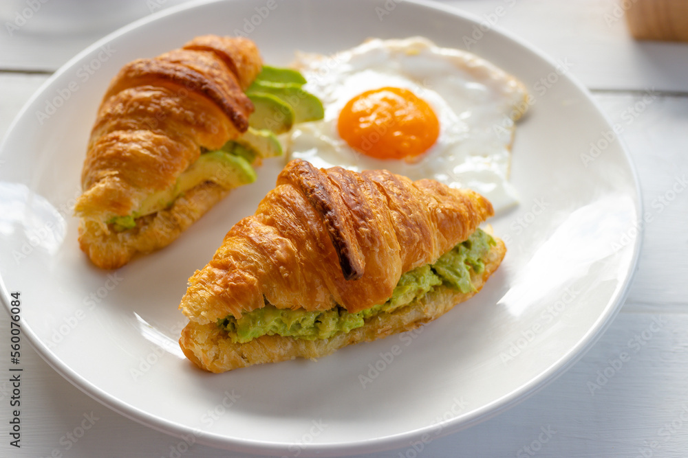 Croissant sandwich with egg, avocado on white dish. breakfast and healthy food concept. Croissant sandwich with egg, avocado on white dish. breakfast and healthy food concept.
