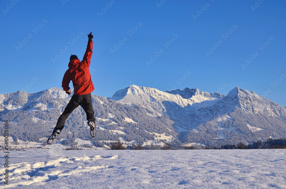 Person mit Jubel und Freudensprung im Schnee, Berge im Panorama