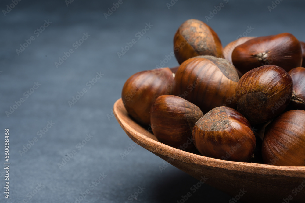 Obraz premium Raw roasted chestnuts on black background 