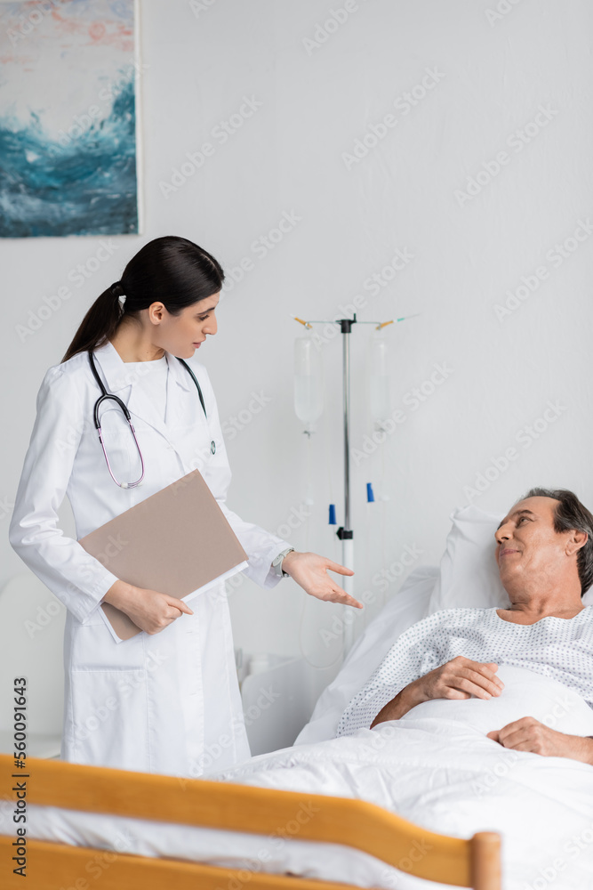 brunette doctor with paper folder talking to elderly patient in clinic. brunette doctor with paper folder talking to elderly patient in clinic.