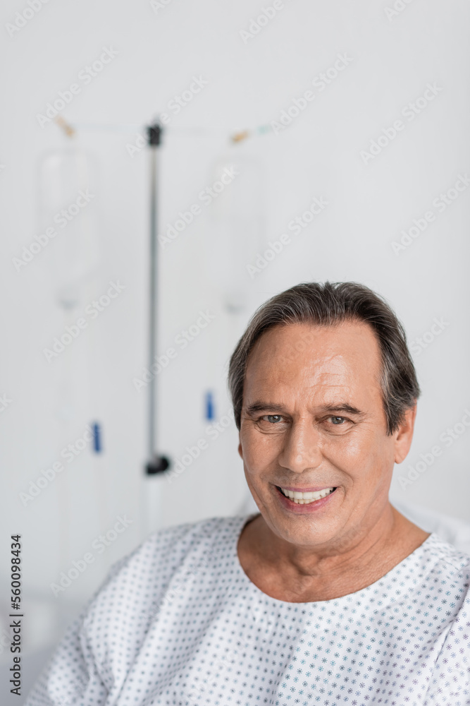 Positive grey haired patient looking at camera in blurred hospital ward. Positive grey haired patient looking at camera in blurred hospital ward.