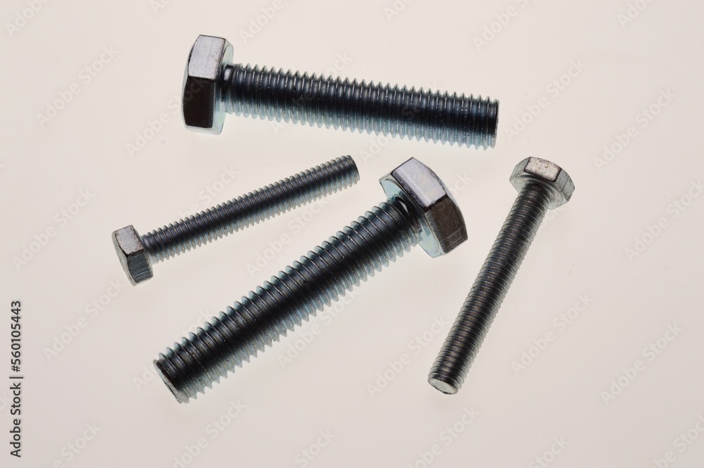 New, chrome-plated bolts and nuts of different sizes lie on a white background. Close-up New, chrome-plated bolts and nuts of different sizes lie on a white background. Close-up