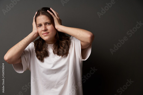 Worried woman with sullen eyebrows holding her head in hands