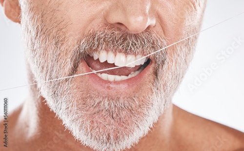 Floss, dental and face of senior man in studio isolated on a gray background. Cleaning, hygiene and elderly male model with product flossing teeth for oral wellness, tooth care and healthy mouth.