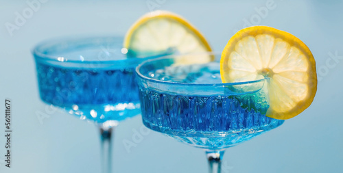 Bild auf Leinwand A glass of delicious blue cocktail Blue Lagoon and yellow lemons on the background of the pool