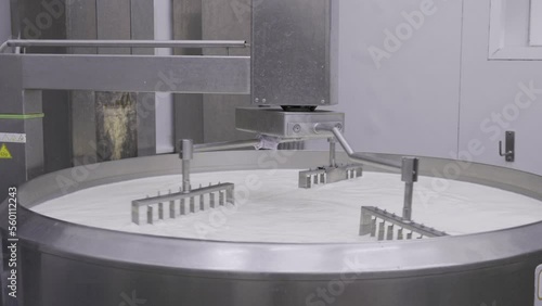 Mechanic arms mixing milk curs in a large industrial size pot at the dairy company